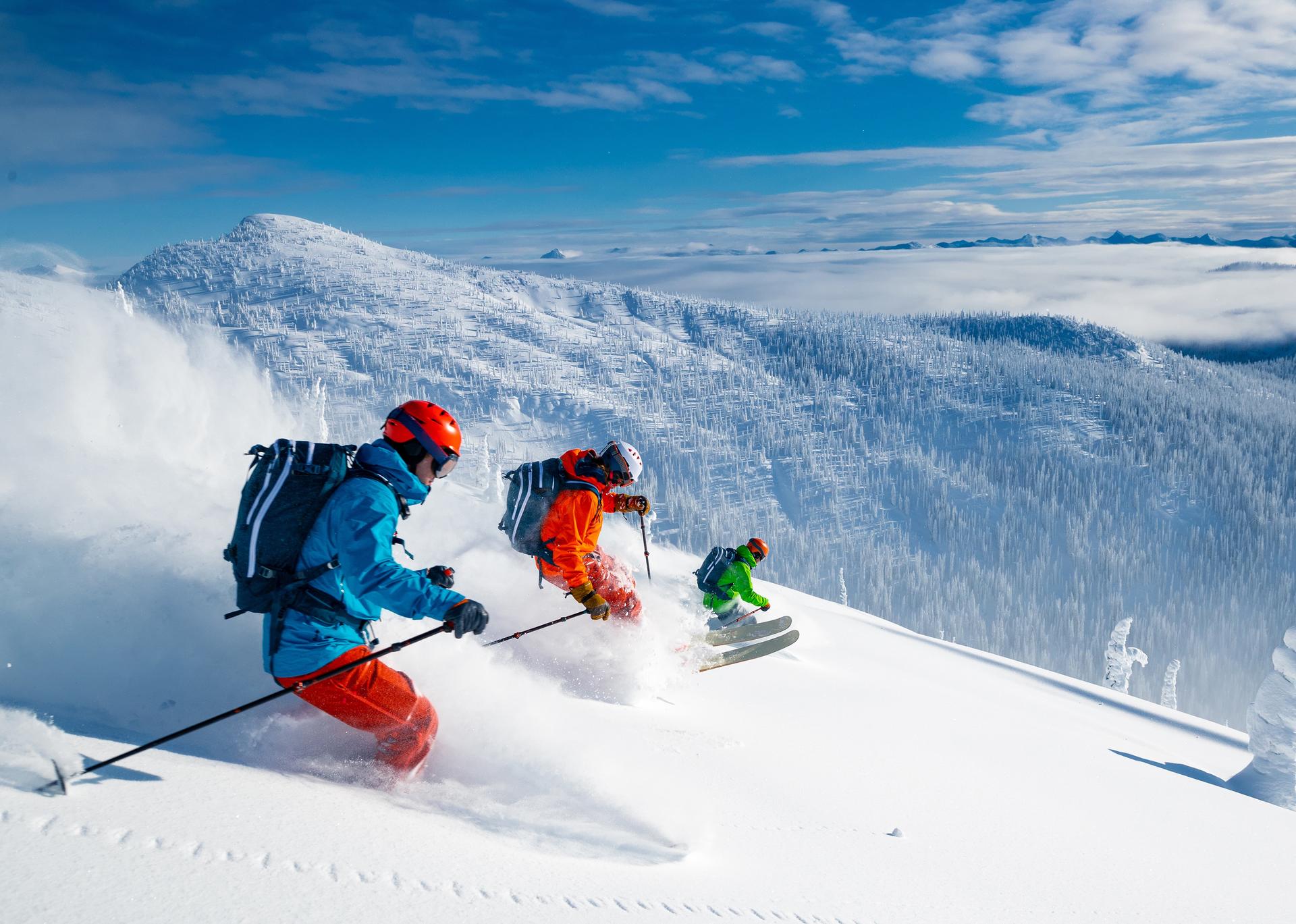 skiers race down a mountain with powder trails