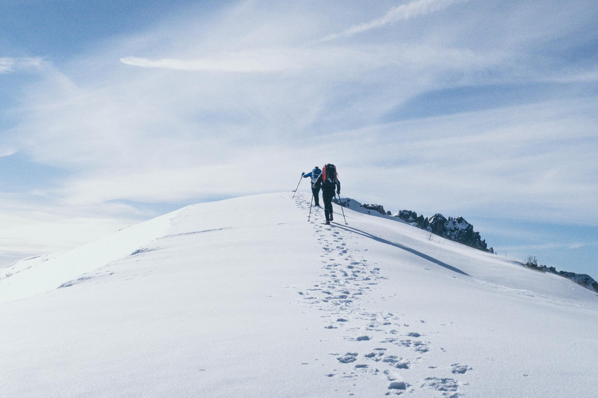 Friends hiking up snowy mountain