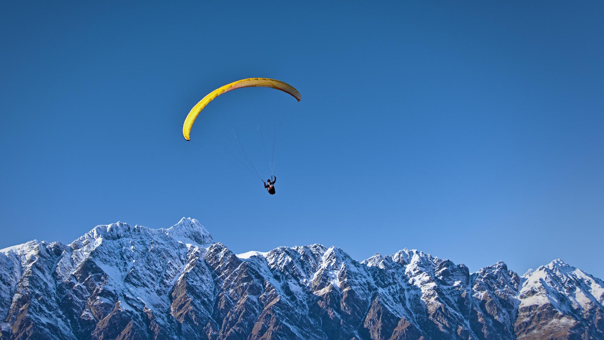 Man soaring above mountains while paragliding 