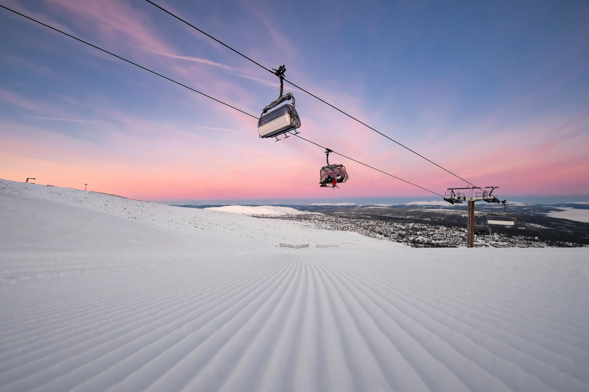 Skiiers being transported to top of mountain on chairlift at sunrise