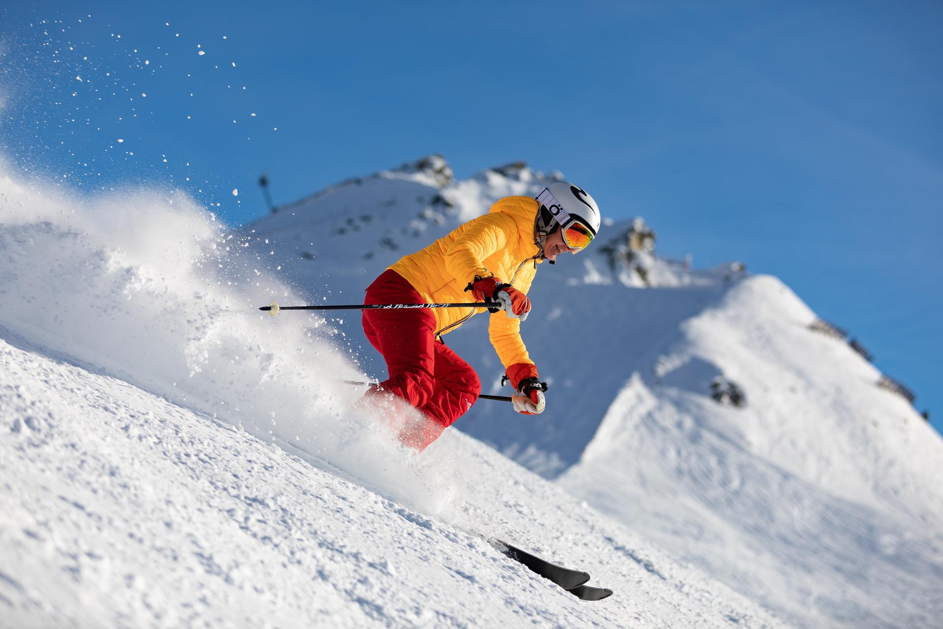 Woman in orange jacket skiing down ski slope